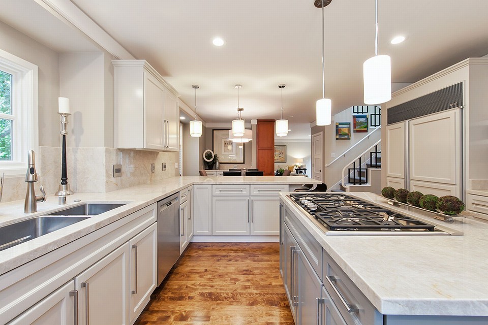 kitchen includes center island, taj mahal slab countertops, custom cabinetry, and top-of-the-line appliances